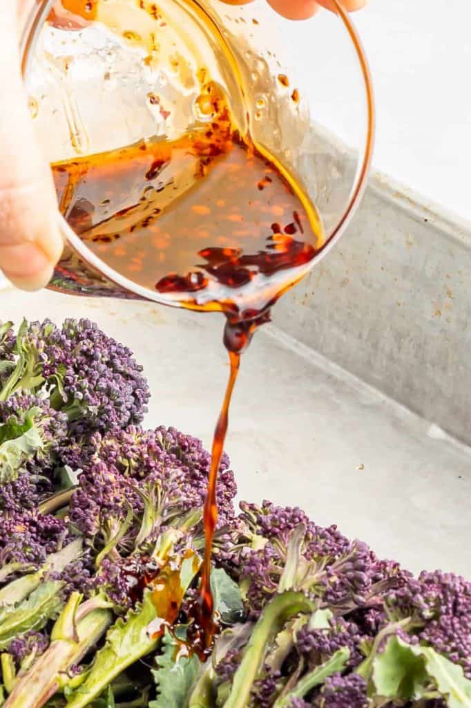 Pouring sesame sauce onto purple broccolin