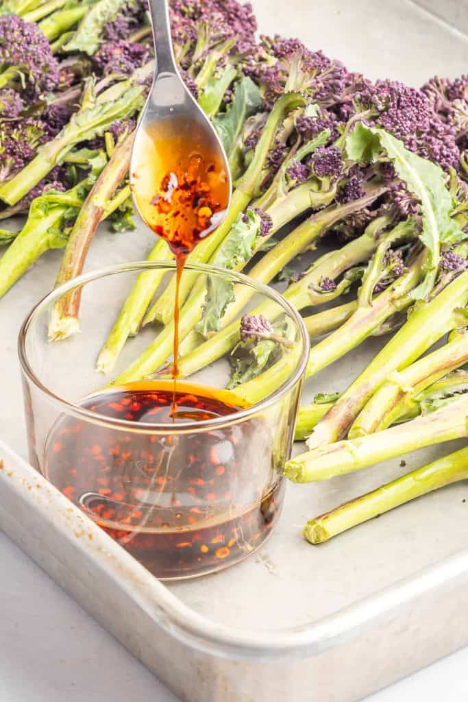 Purple broccolini on baking sheet with closeup of sesame sauce.