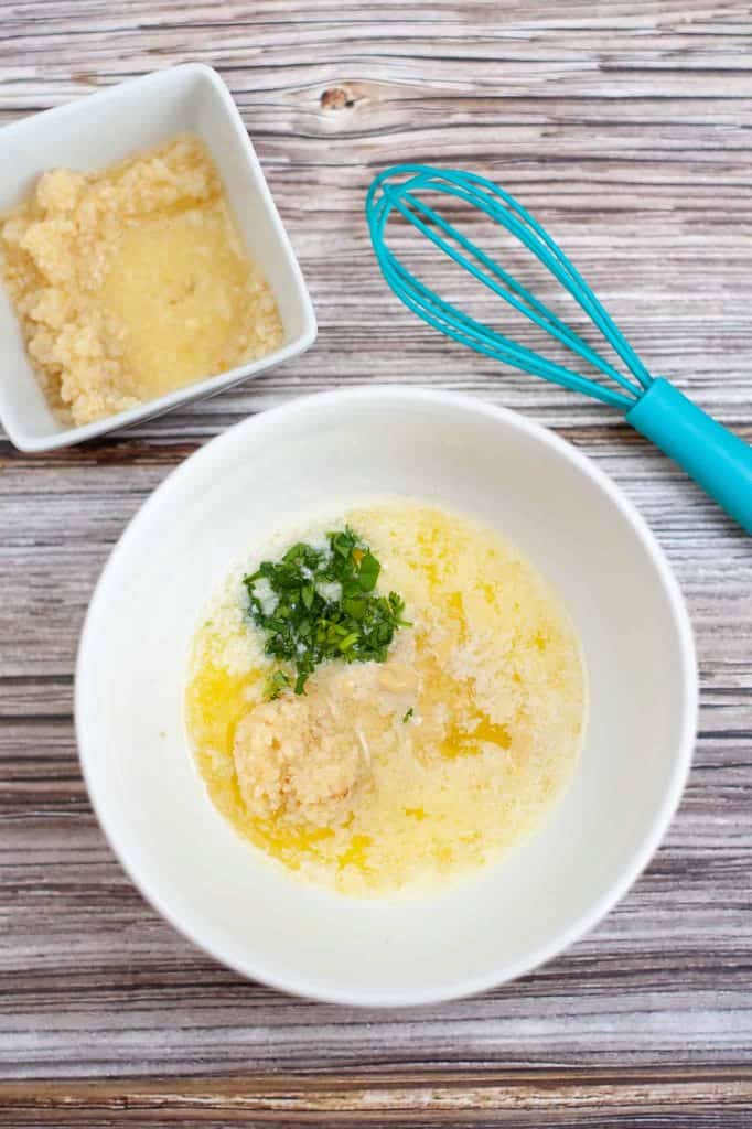 Olive oil, garlic and herbs in a white bowl.