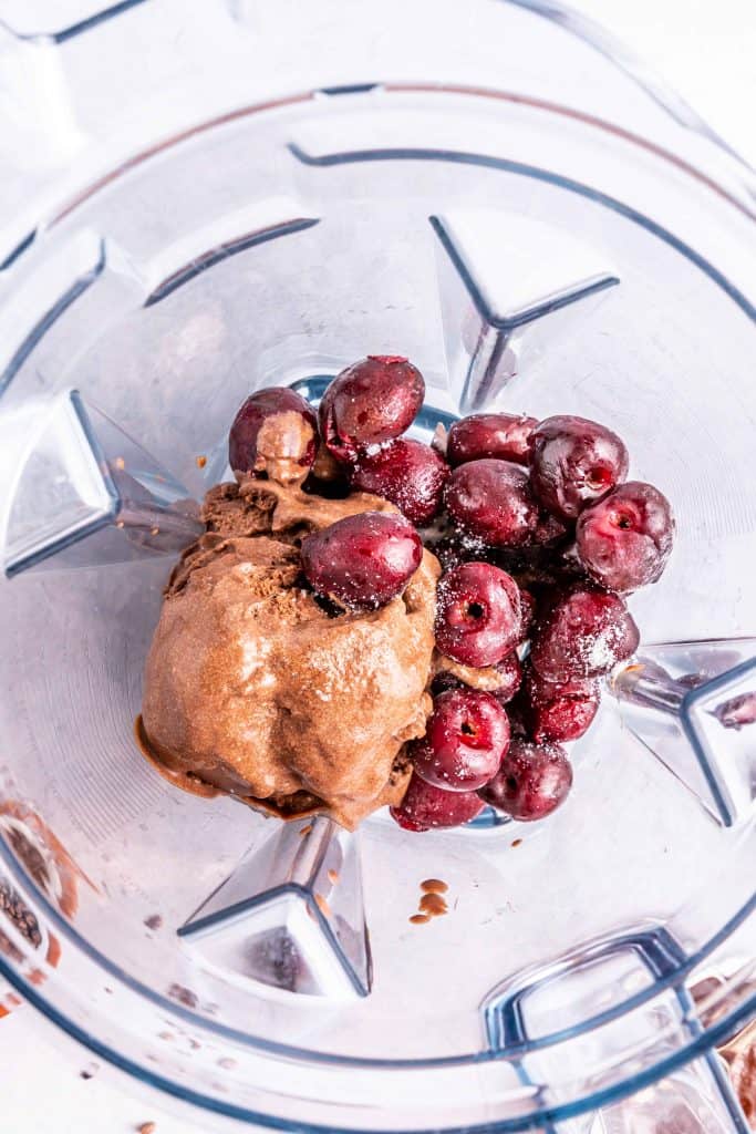 Frozen cherries and chocolate ice cream in a blender.