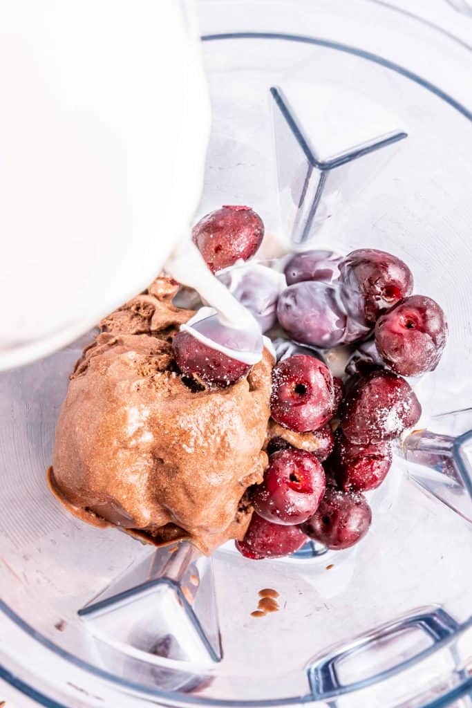 Adding milk to frozen cherries and chocolate ice cream.