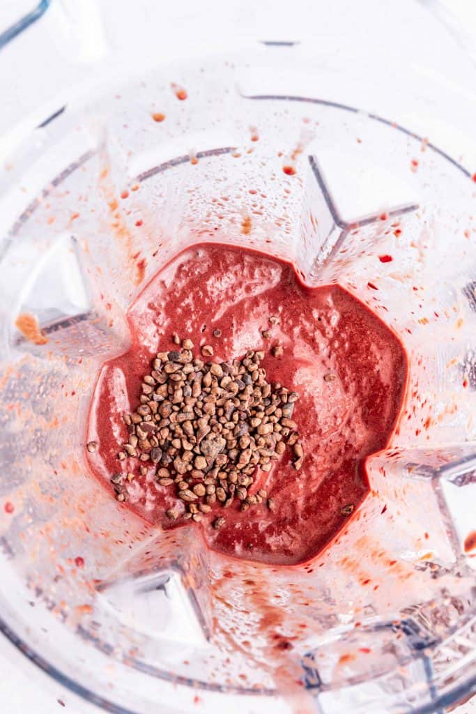 Cherry milkshake in a bender with cacao nibs.