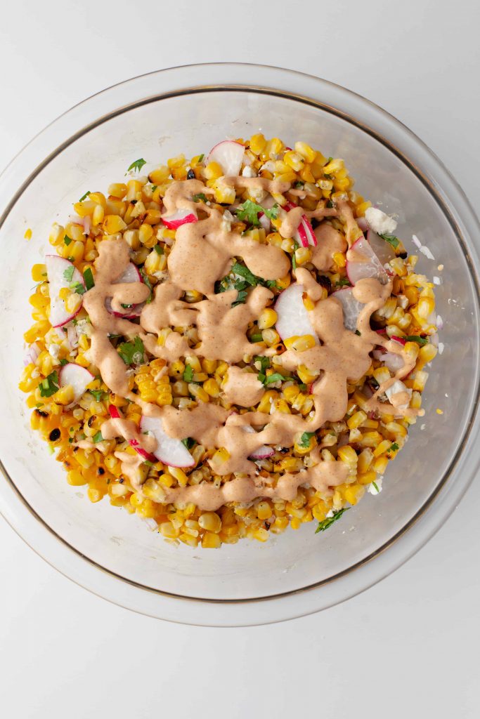 Corn salad with dressing on top of it.