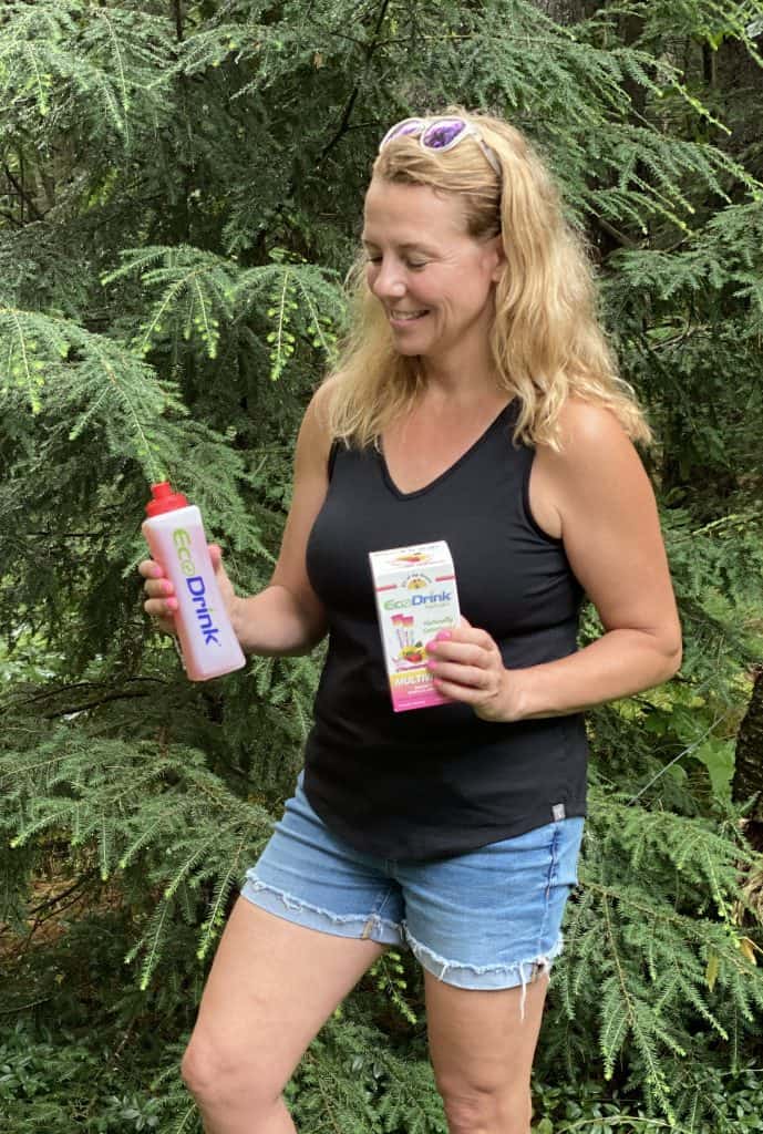 Woman holding Eco Drinks Naturals Box and bottle with drink in it.