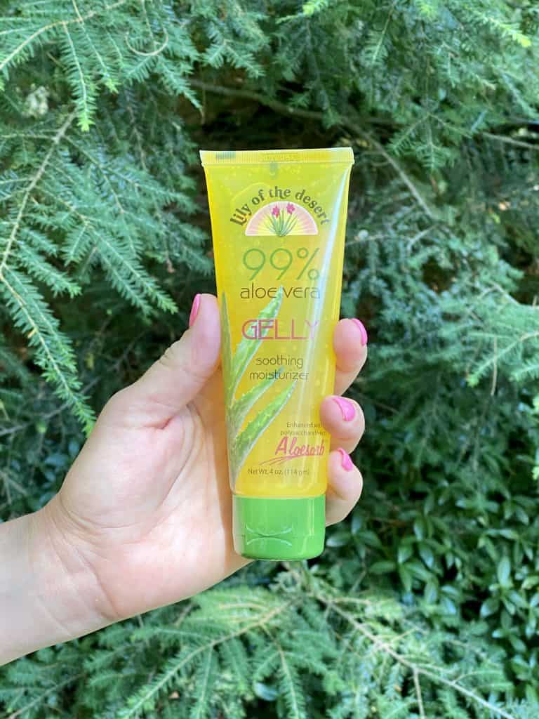 Holding up a tube of Lily of the Desert Aloe Gelly