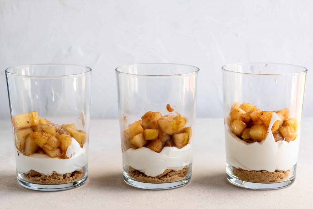Layering apple pie parfaits in glass cups.