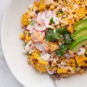 Corn in bowl with avocado and radish slices.