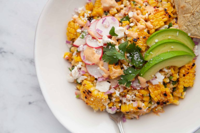 Corn in bowl with avocado and radish slices.