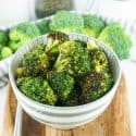 Air fryer broccoli in a white bowl with gray stripes on a cutting board.