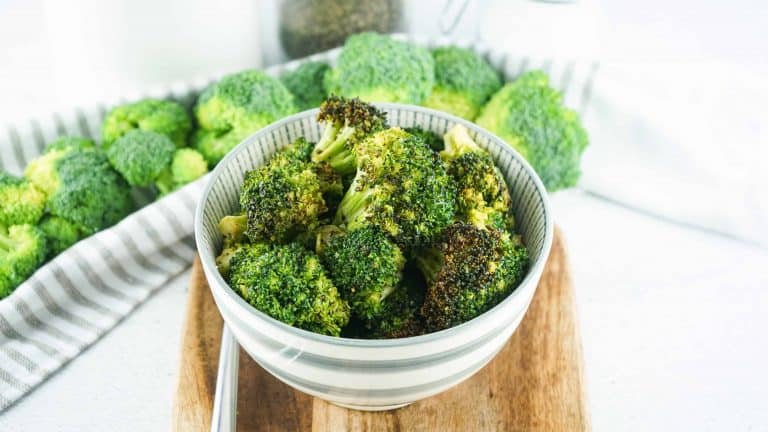 Air fryer broccoli in a white bowl with gray stripes on a cutting board.