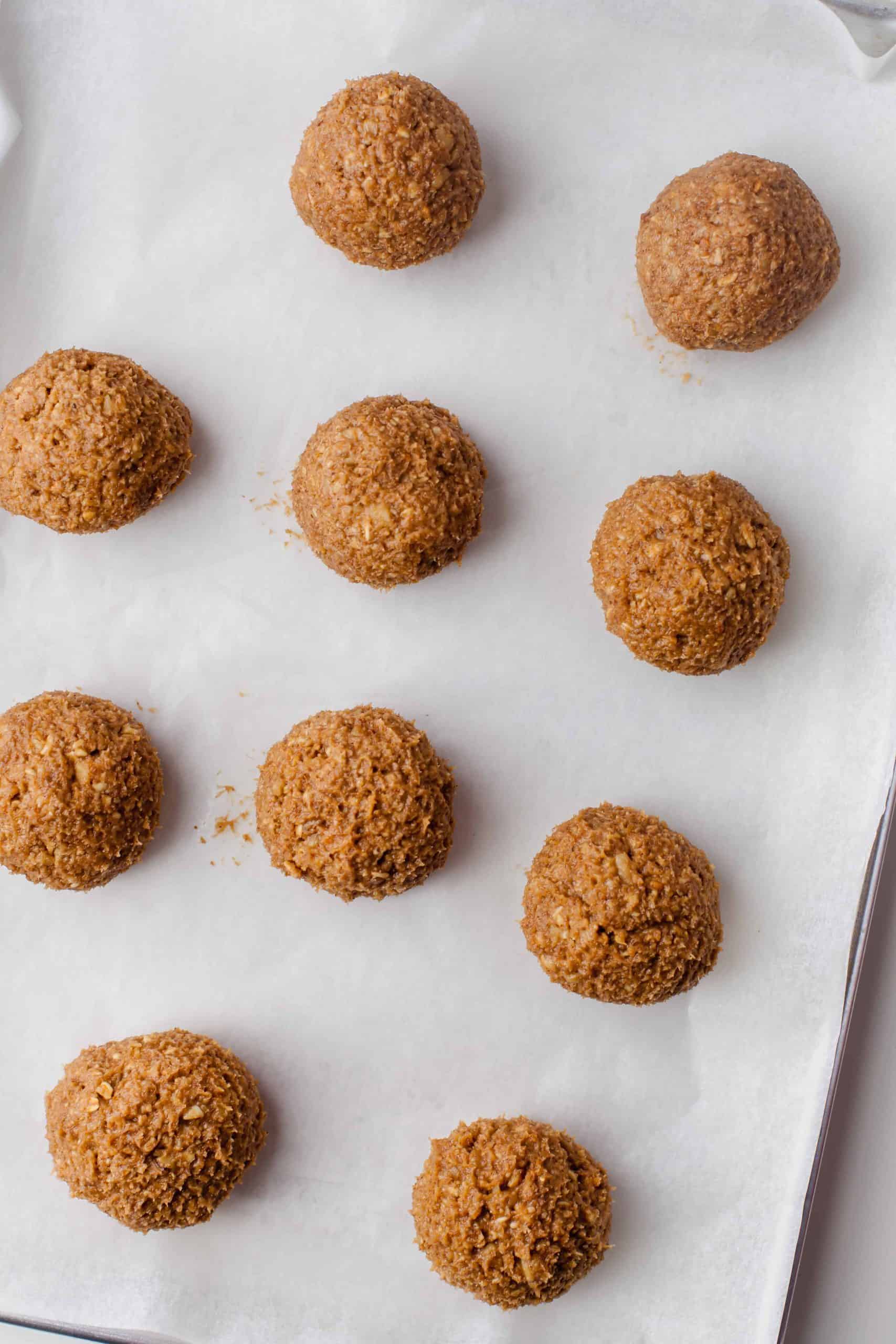 Apple cookie dough balls on cookie sheet lined with parchment paper.