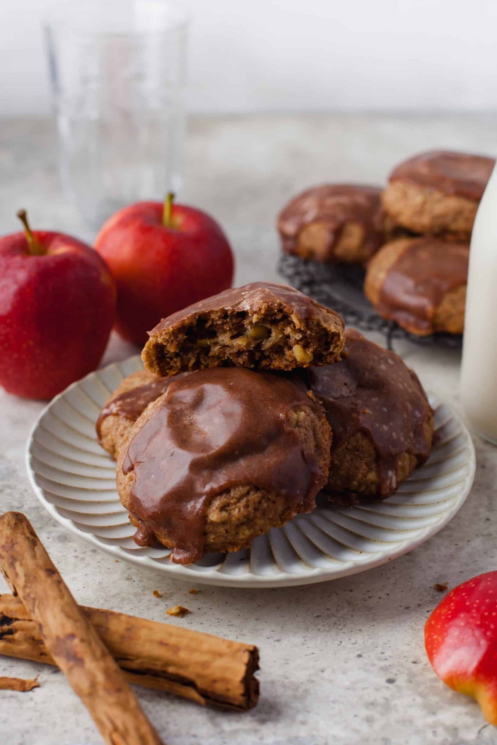 Apple filled cookies on a white plate with one cookie broken in half to show the apple pie filling inside.