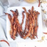 Overhead view of crispy twisted bacon on a white plate.