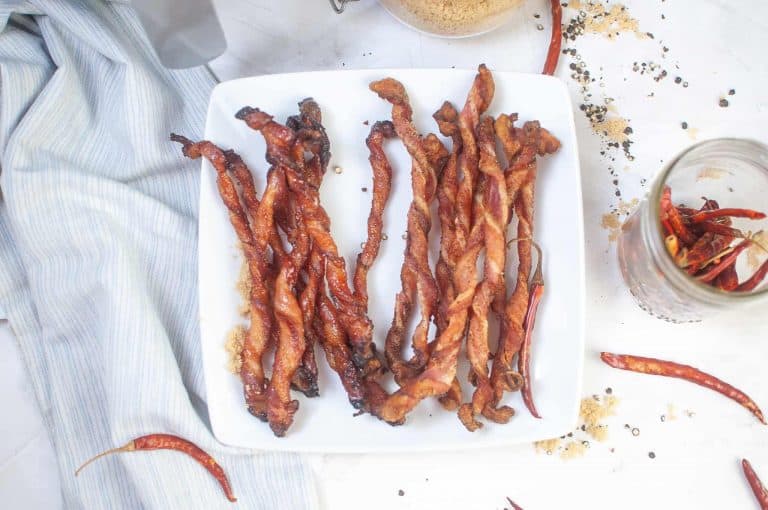 Overhead view of crispy twisted bacon on a white plate.
