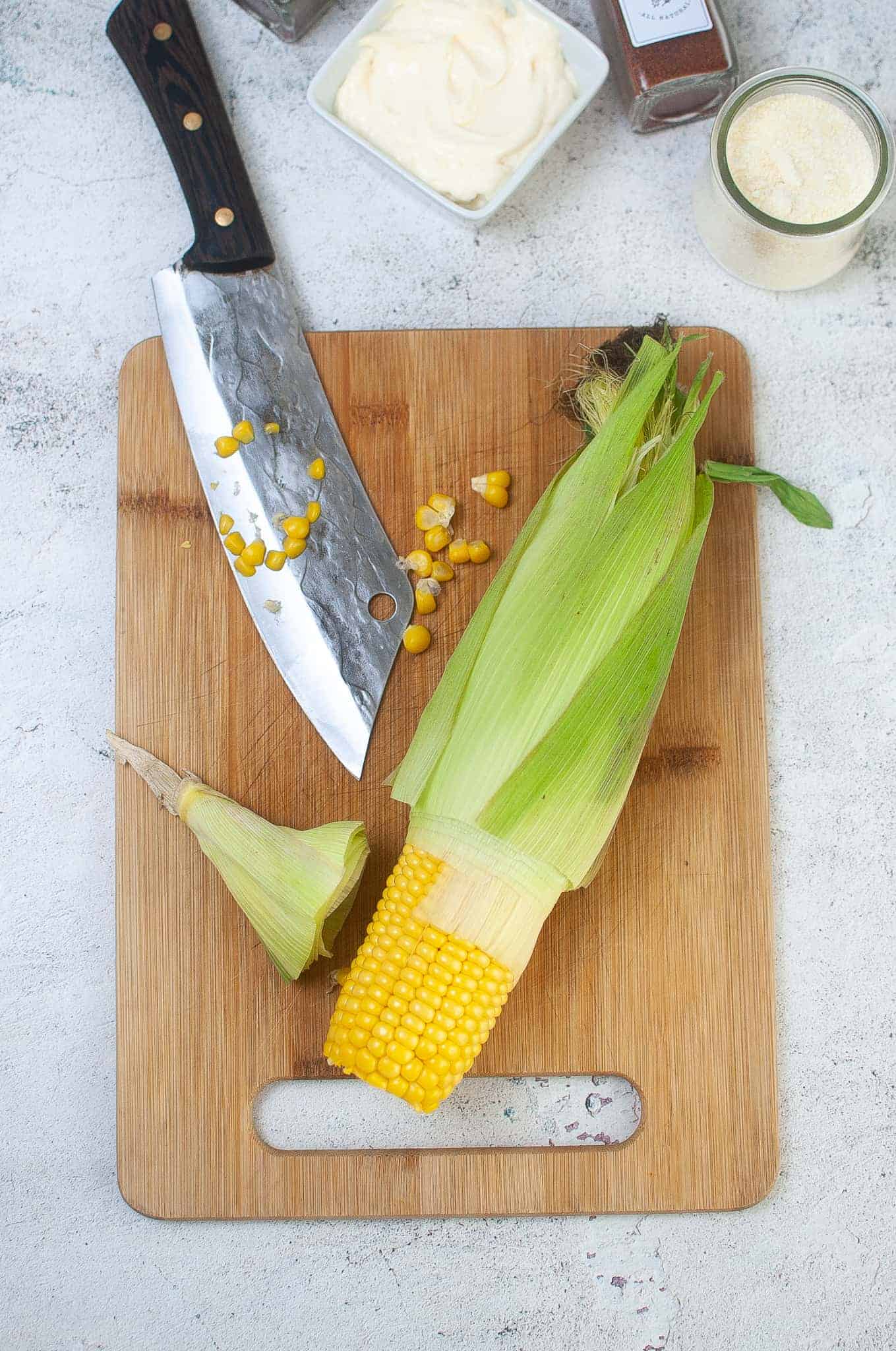 Cutting off base of corn with a clever style knife.