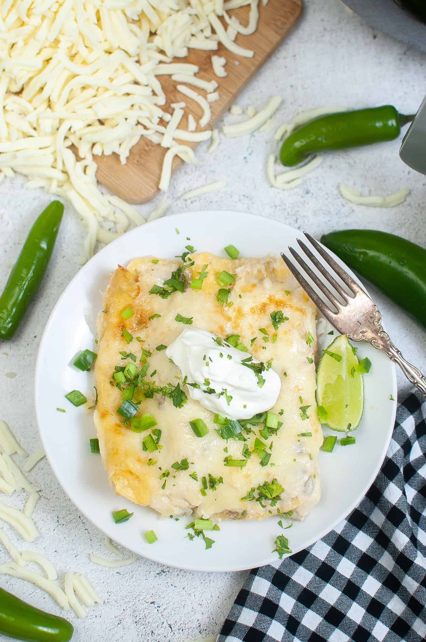 Overhead photo of cheese enchiladas with sour cream and cilantro sprinkled on top.