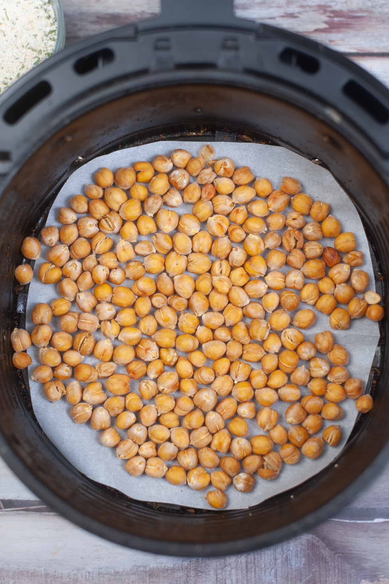 Overhead view of roasted chickpeas in air fryer basket.