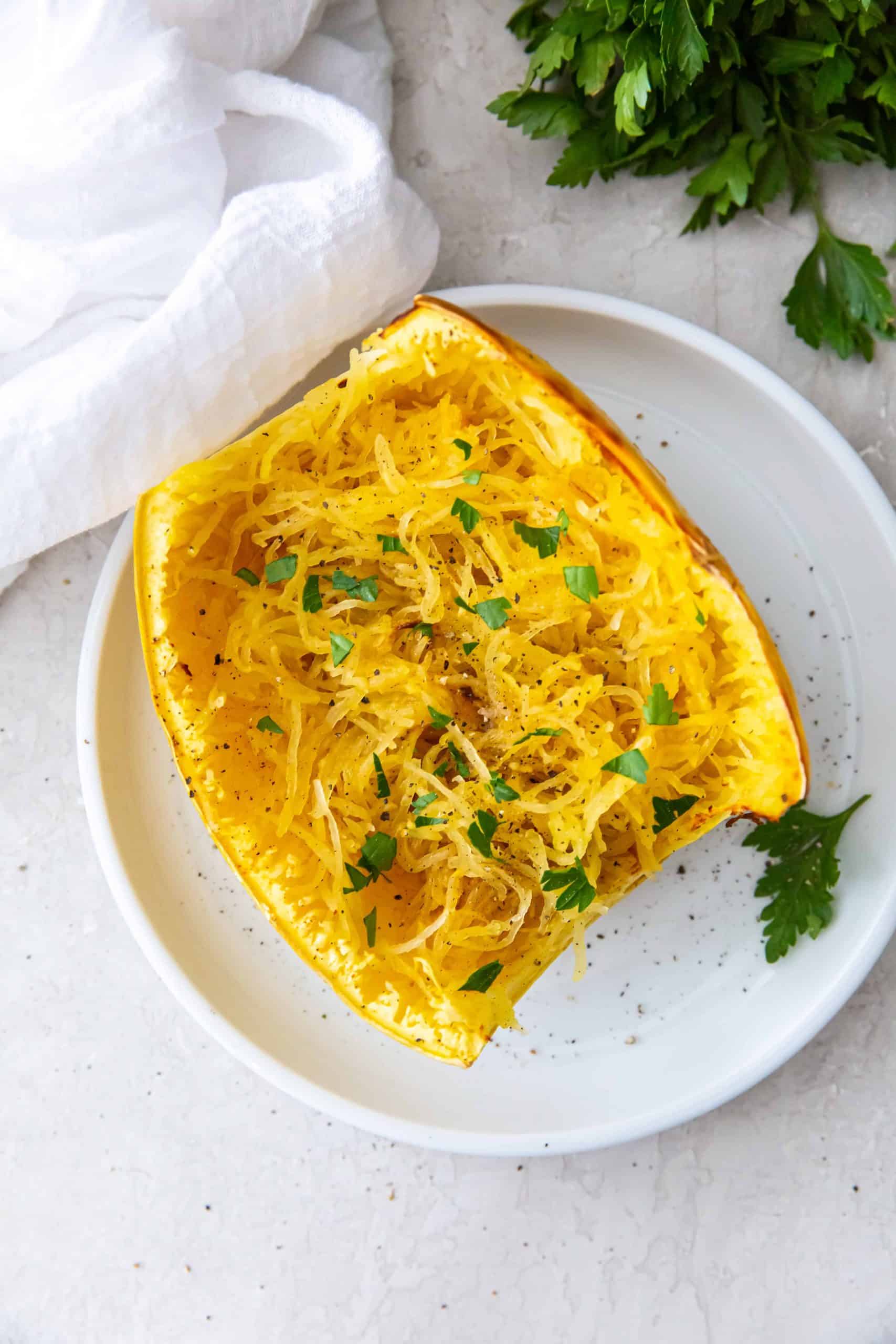Overhead view of spaghetti squash on a plate with fresh herbs.