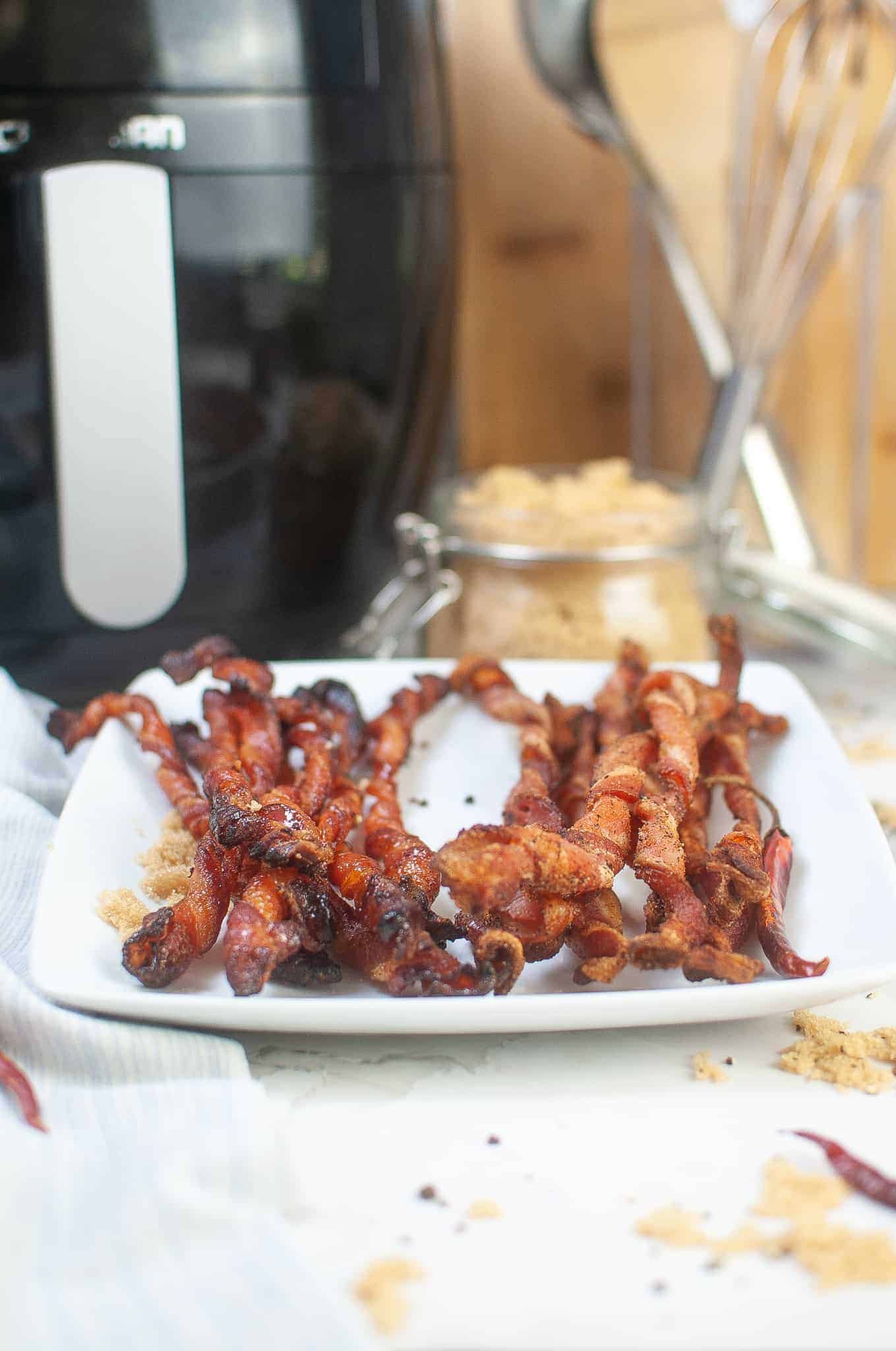 Brown sugar coated bacon twists on a white plate.