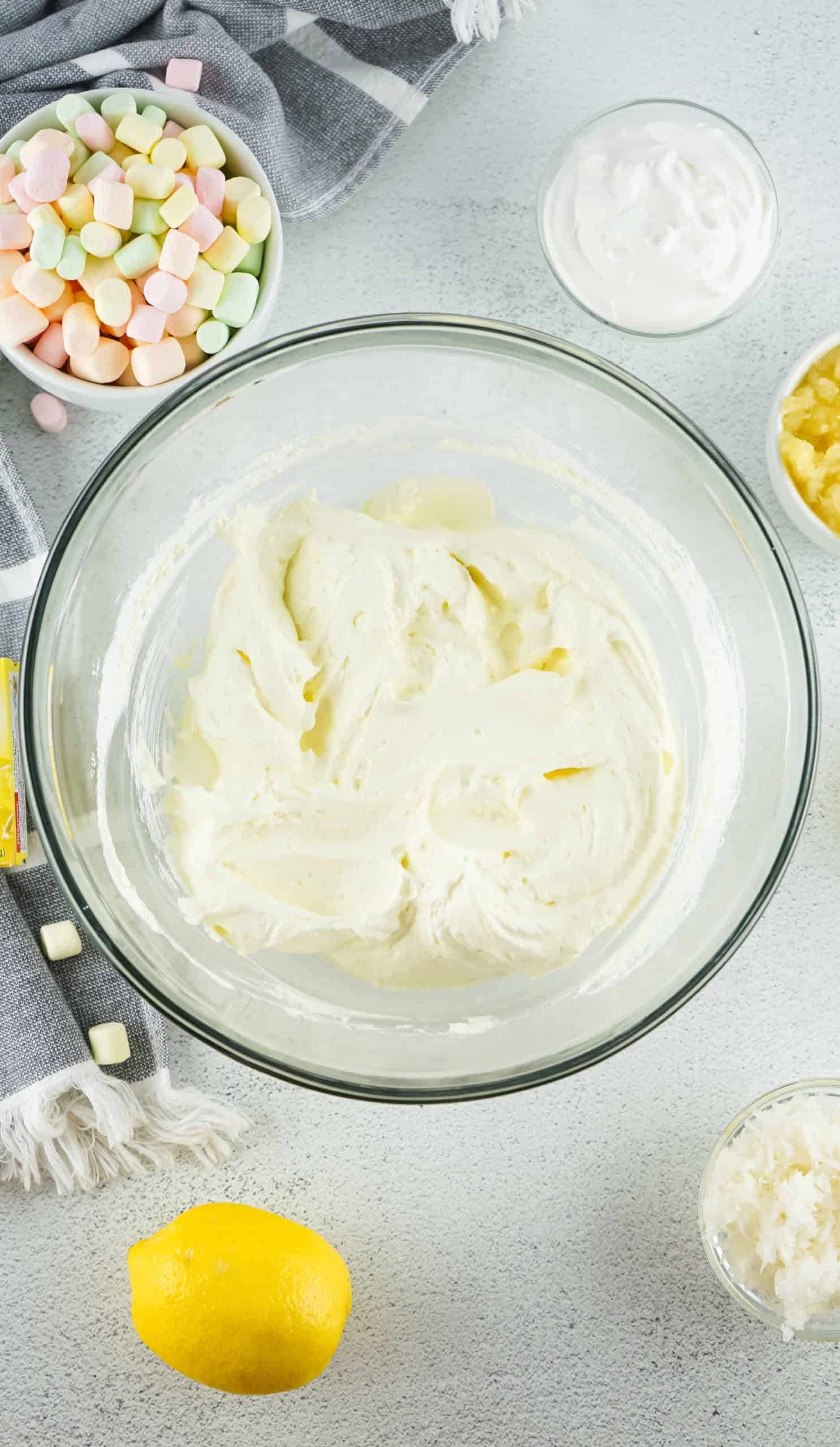 Overhead view of whipped cream and lemon jello mixed in a bowl.