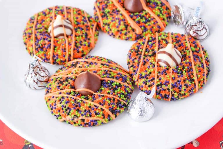 Halloween cookies with sprinkles and Hershey and Hugs Kisses on a plate.