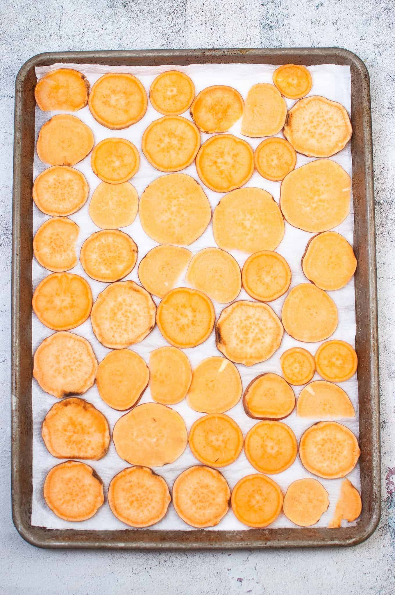 Sweet potato slices in a single layer on a sheet pan.