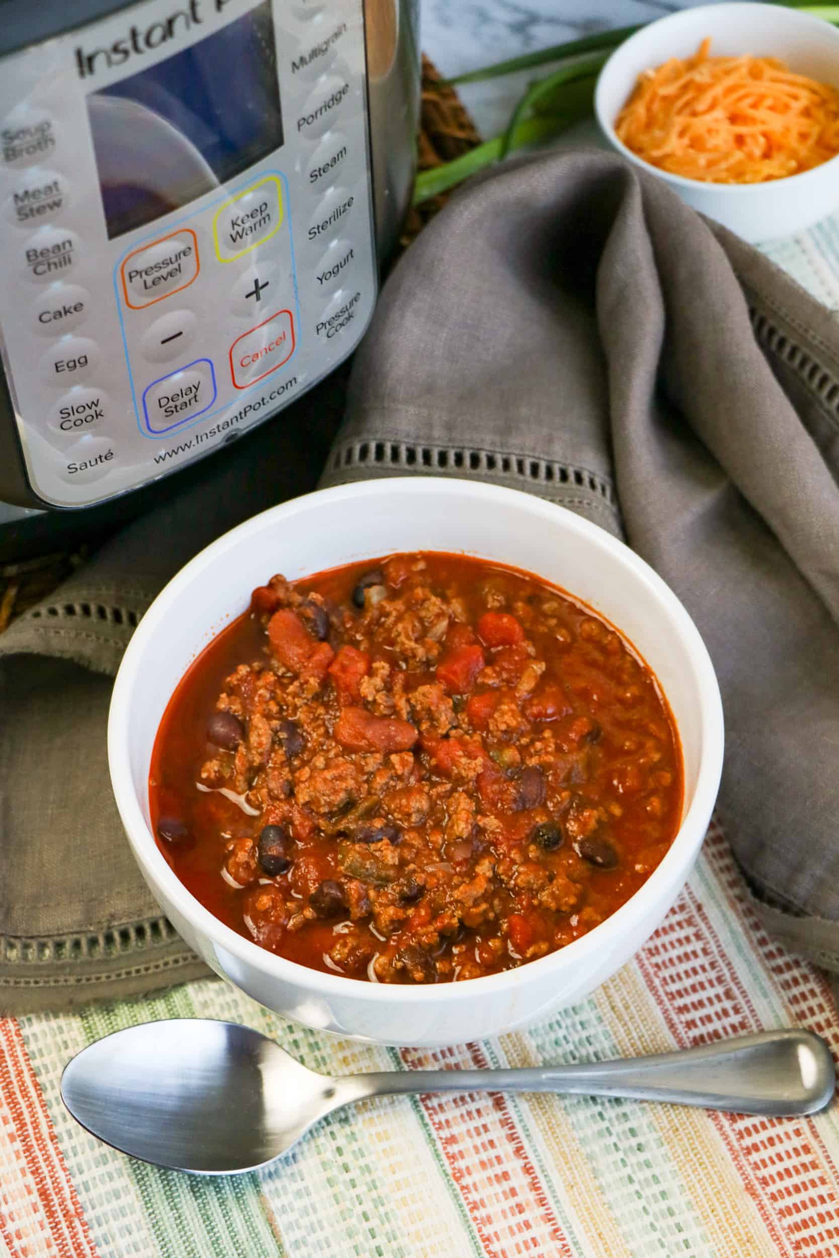Chili in a white bowl in front of the Instant Pot.