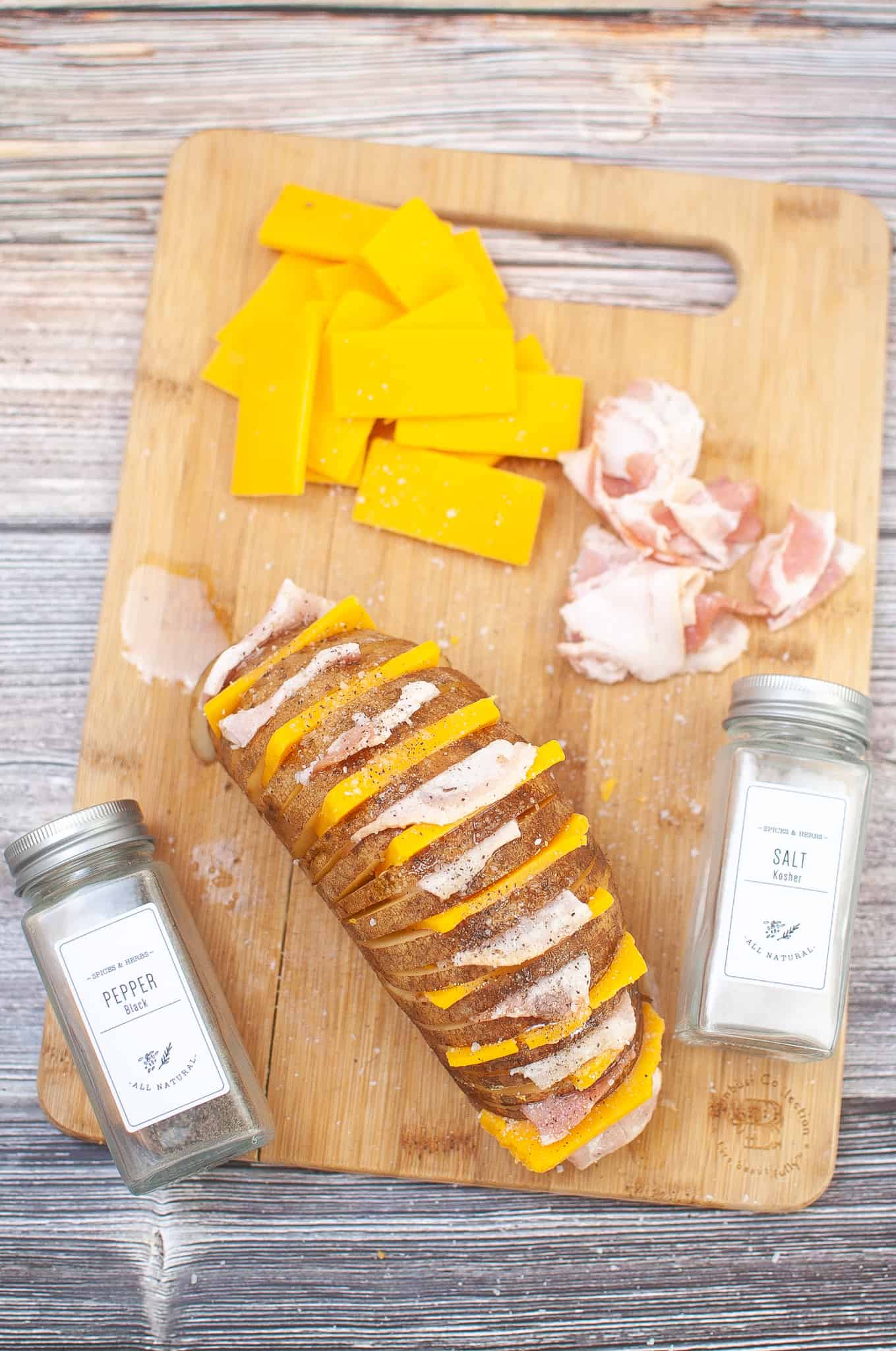 Air Fryer Hasselback potato with bacon and cheese on a cutting board.