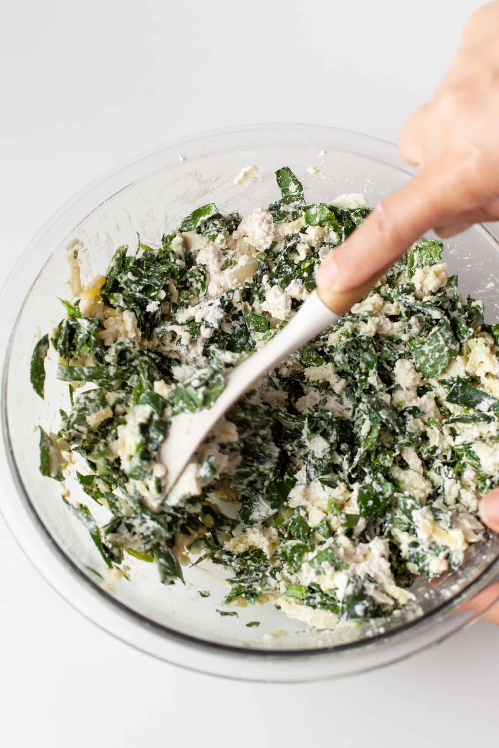 Zucchini Lasagna filling in a glass bowl with a spoon.