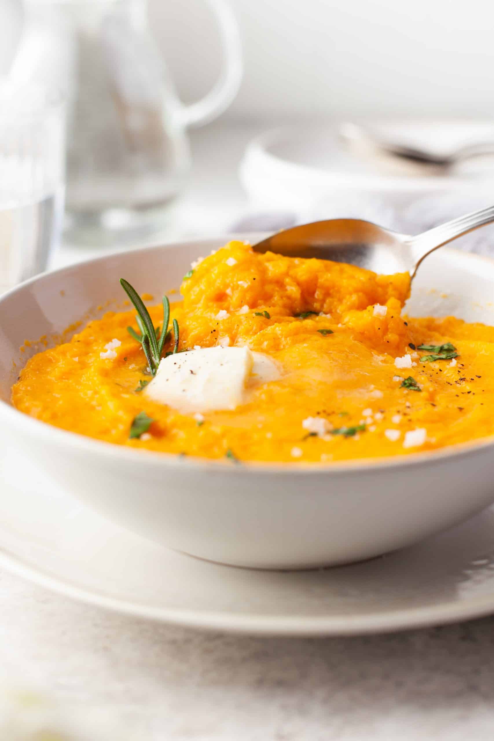 Bowl of mashed butternut squash with butter and herbs. Spoon in bowl,
