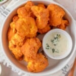 Overhead view Buffalo Cauliflower in a bowl with blue cheese dressing.