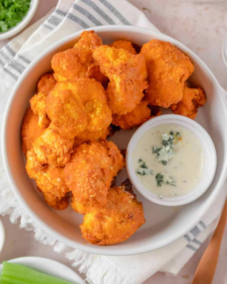 Overhead view Buffalo Cauliflower in a bowl with blue cheese dressing.