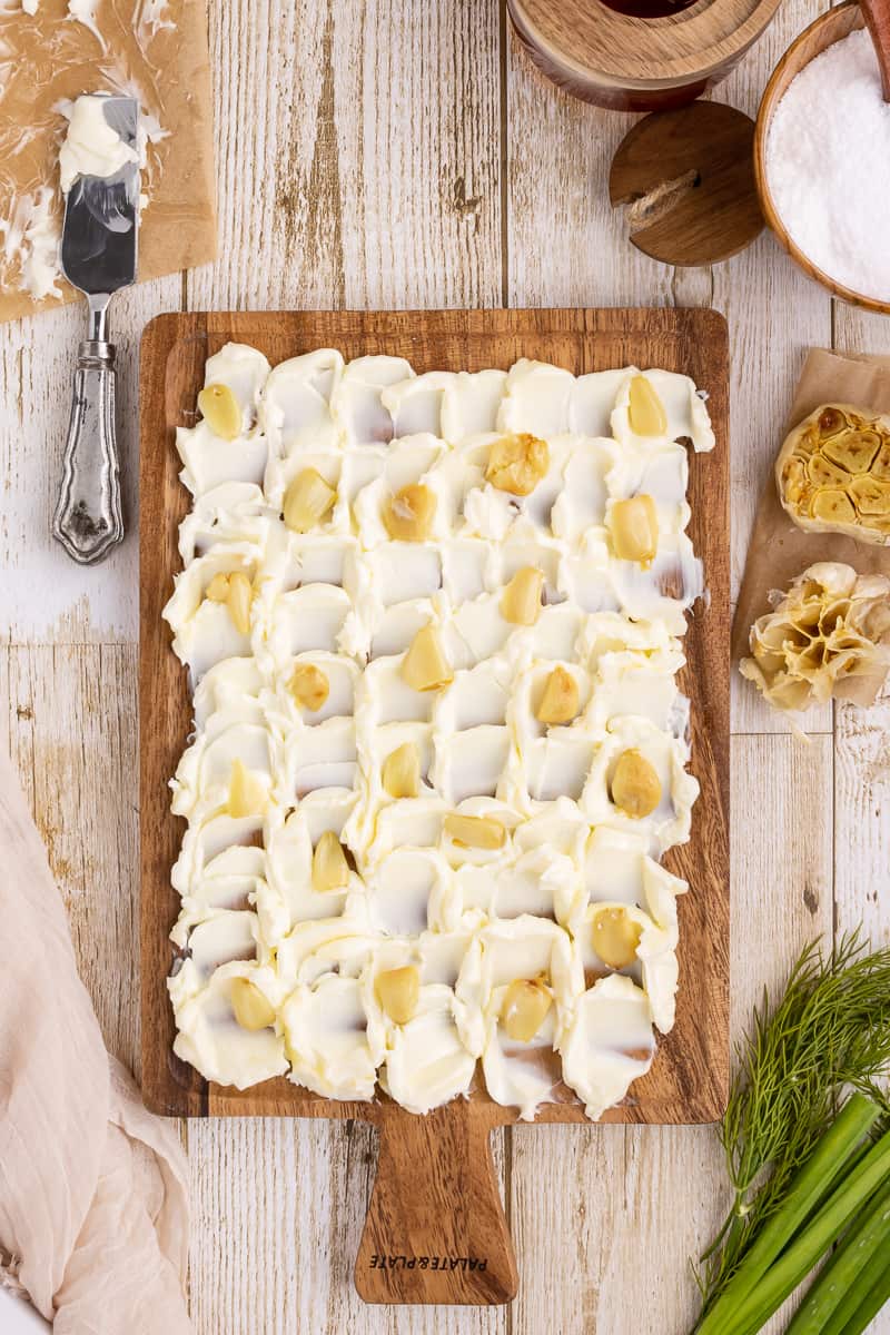 Butter on a cutting board with roasted garlic.
