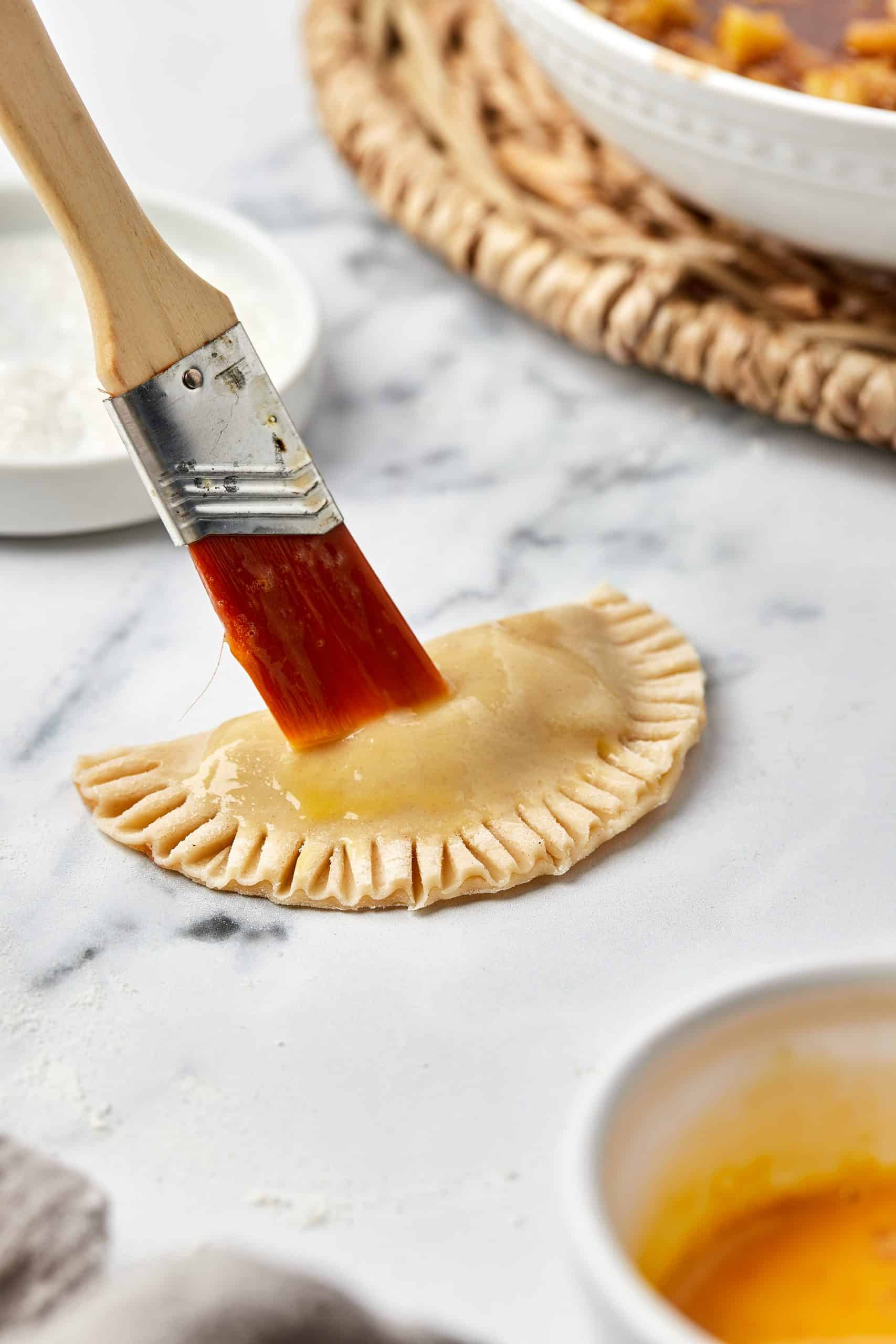 Egg wash brushed onto mini apple pies.