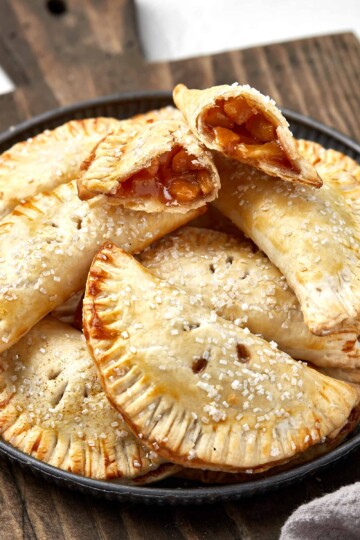 Apple hand pie on a cutting board with one broken in half.