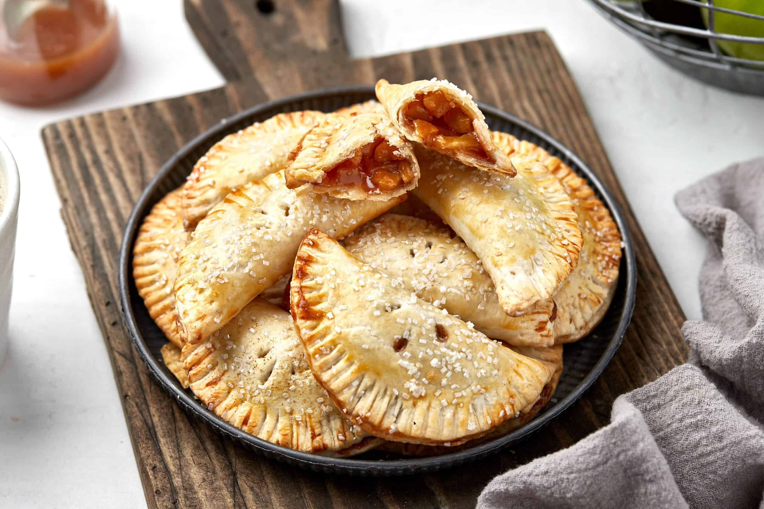 Apple hand pie on a cutting board with one broken in half.