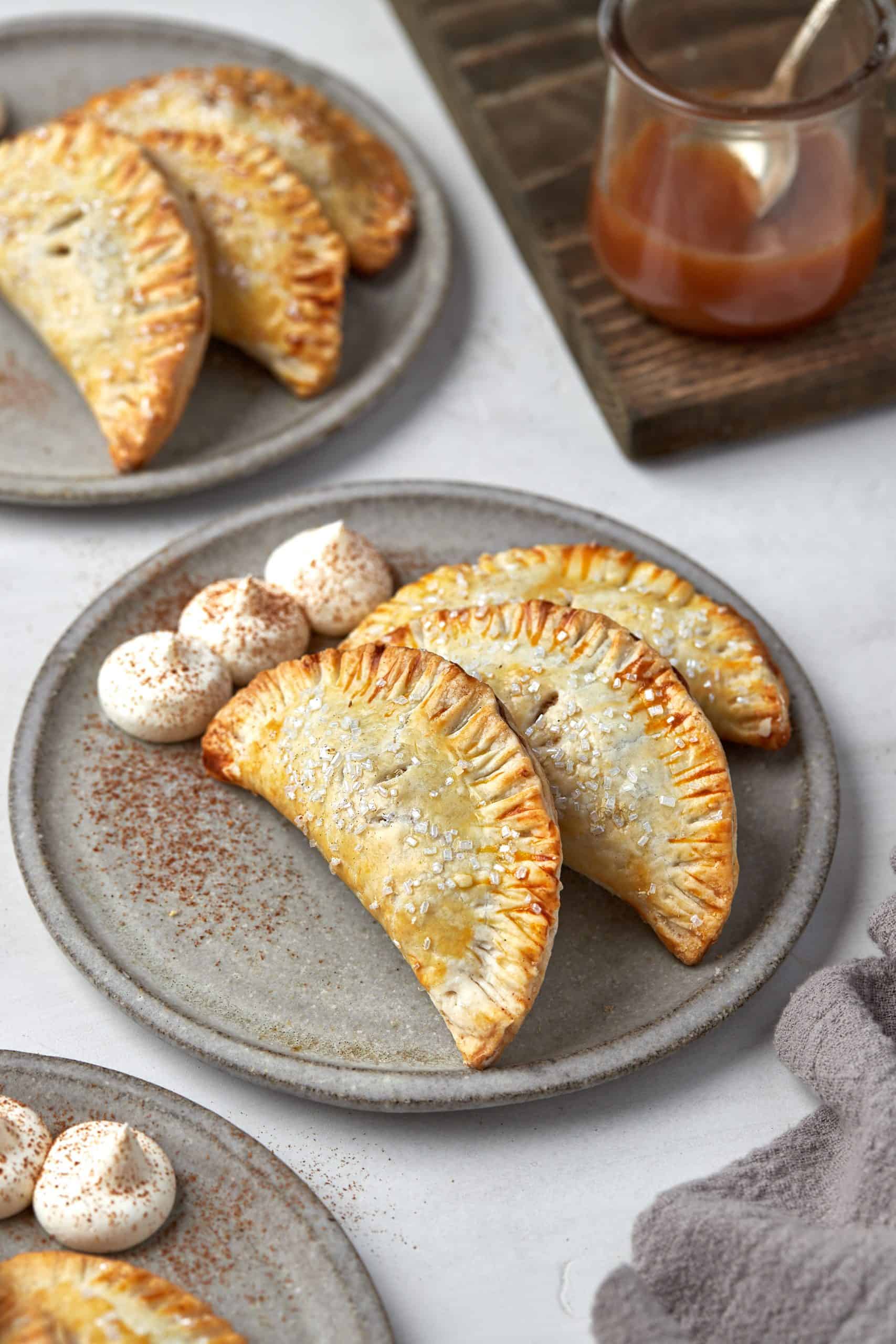 Air fryer apple hand pies on a plate with dollups of whipped cream.