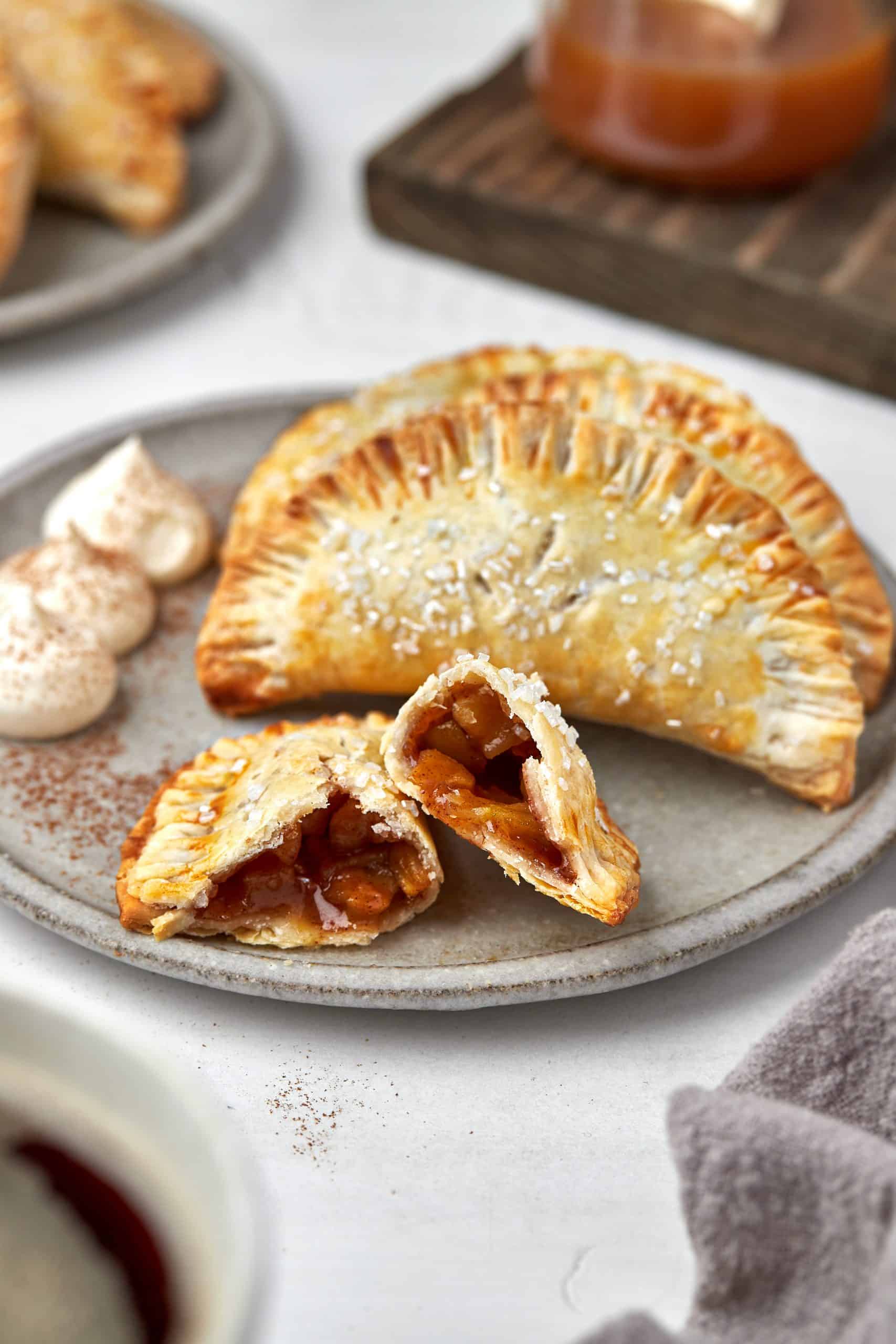 Apple hand pies on a gray plate with one broken in half.