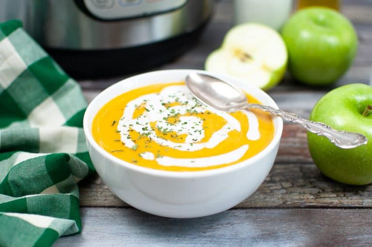 Butternut squash soup in bowl with coconut milk drizzled on it.