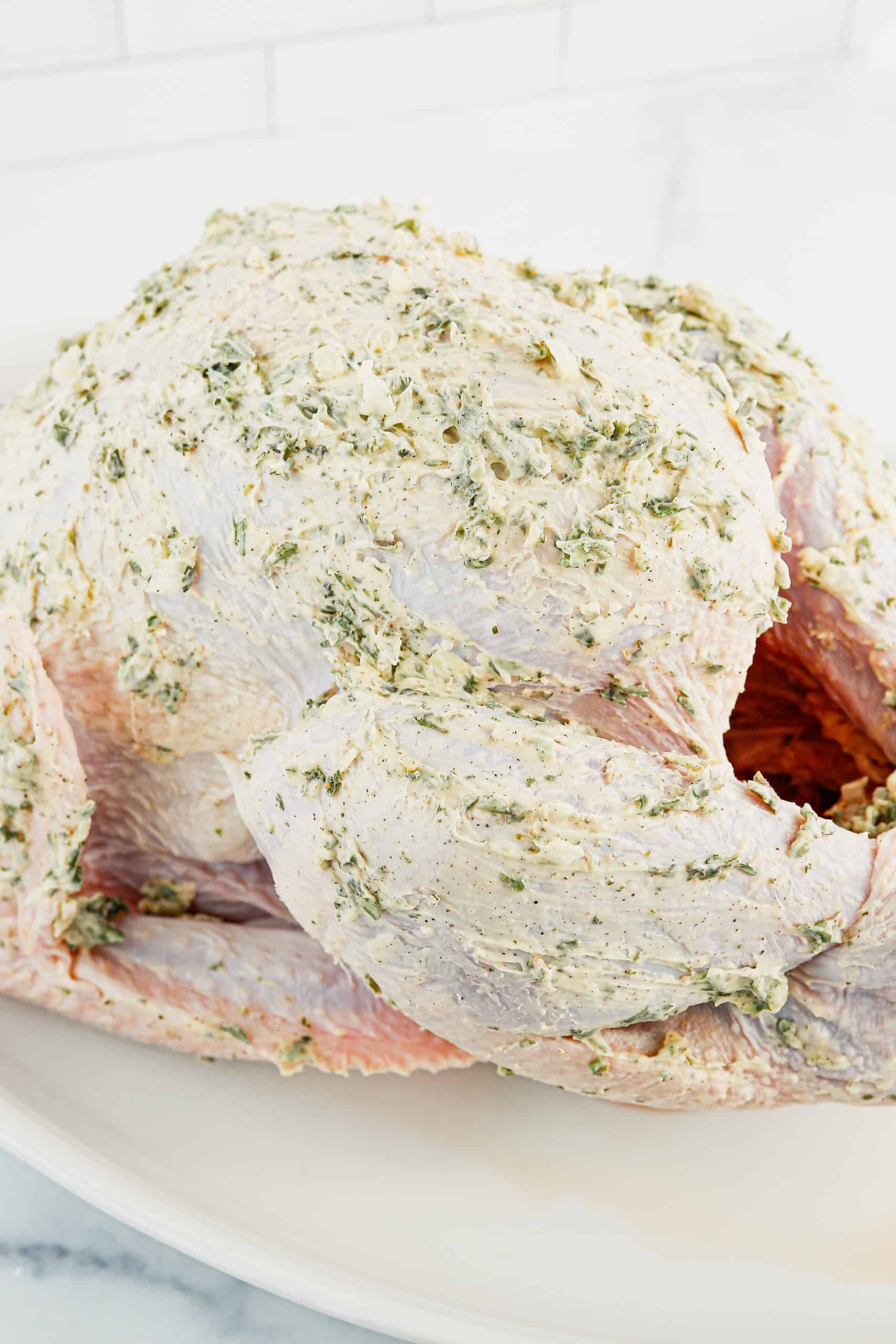 Uncooked turkey rubbed with herb butter ready for the oven.
