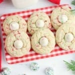 Overhead view of sugar cookie blossoms on a red and white heckered plate.