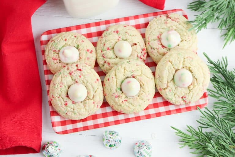 Overhead view of sugar cookie blossoms on a red and white heckered plate.