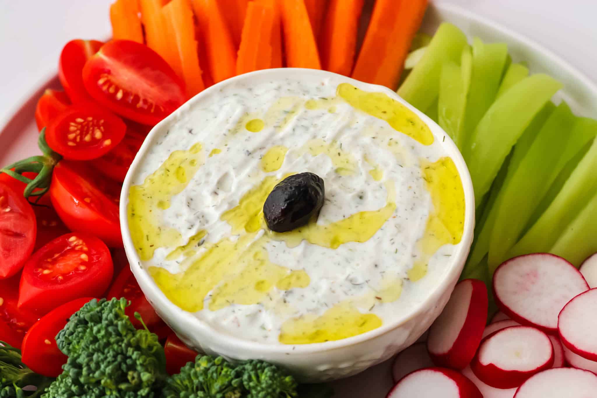 Greek yogurt dip surrounded by vegetables.