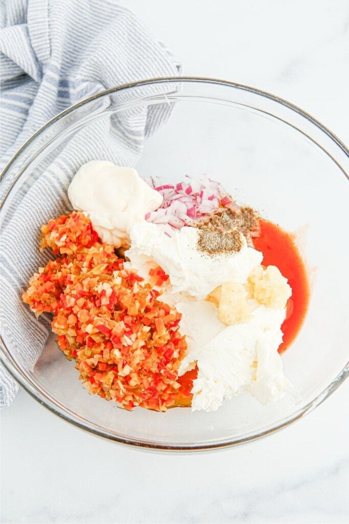 Mixing chopped giardiniera, mayonnaise, and cream cheese in a bowl.