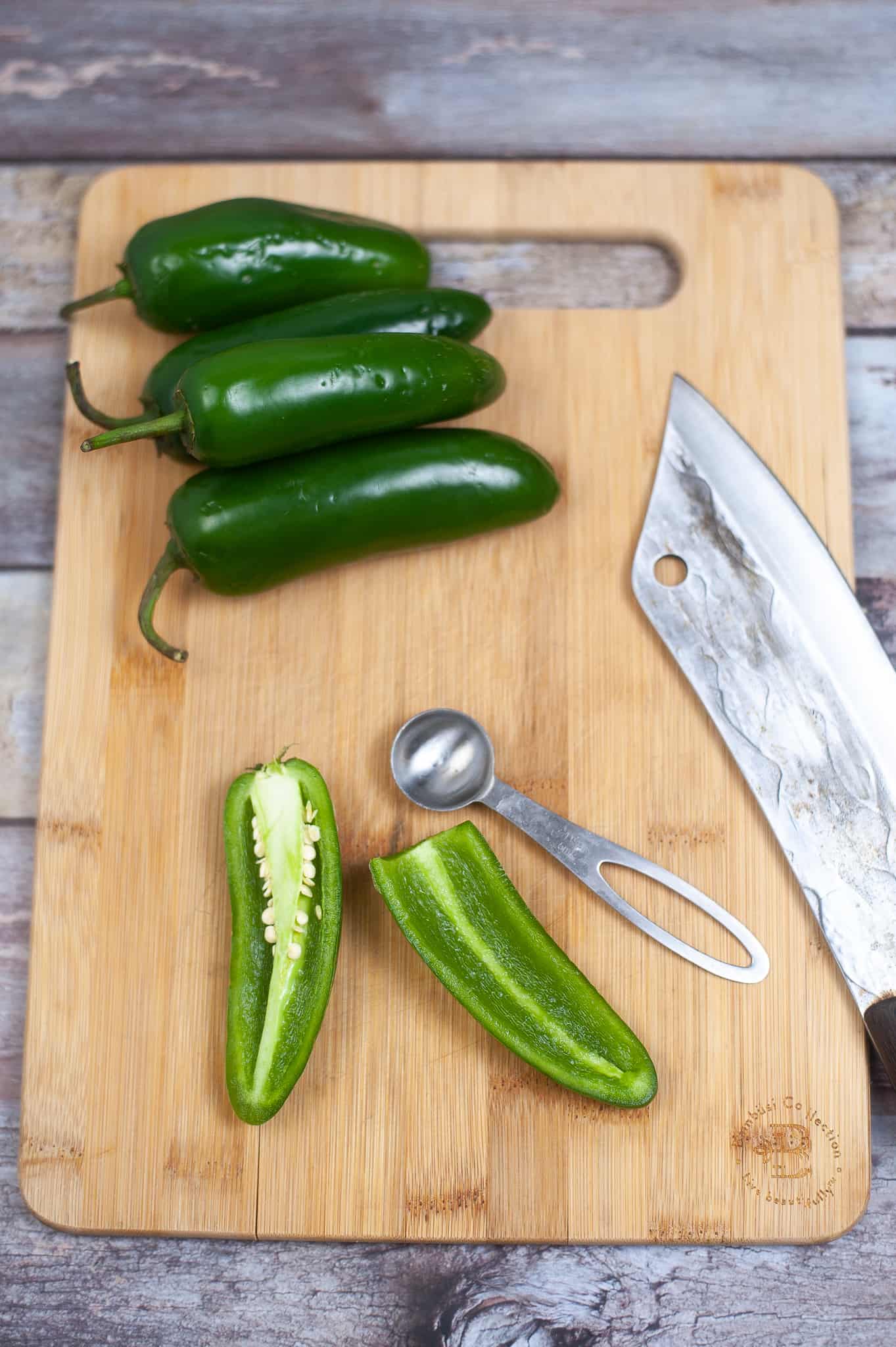 Jalape&ntilde;os sliced in half on a cutting board.