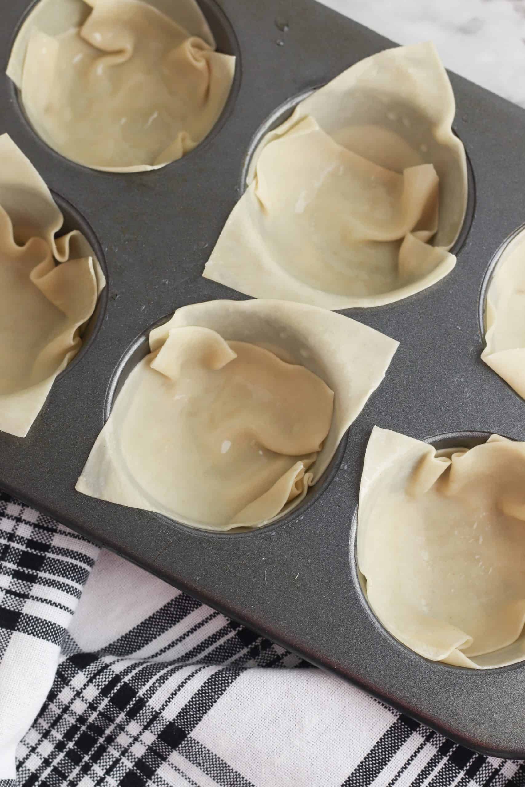 Eggroll wrappers in a muffin ti.