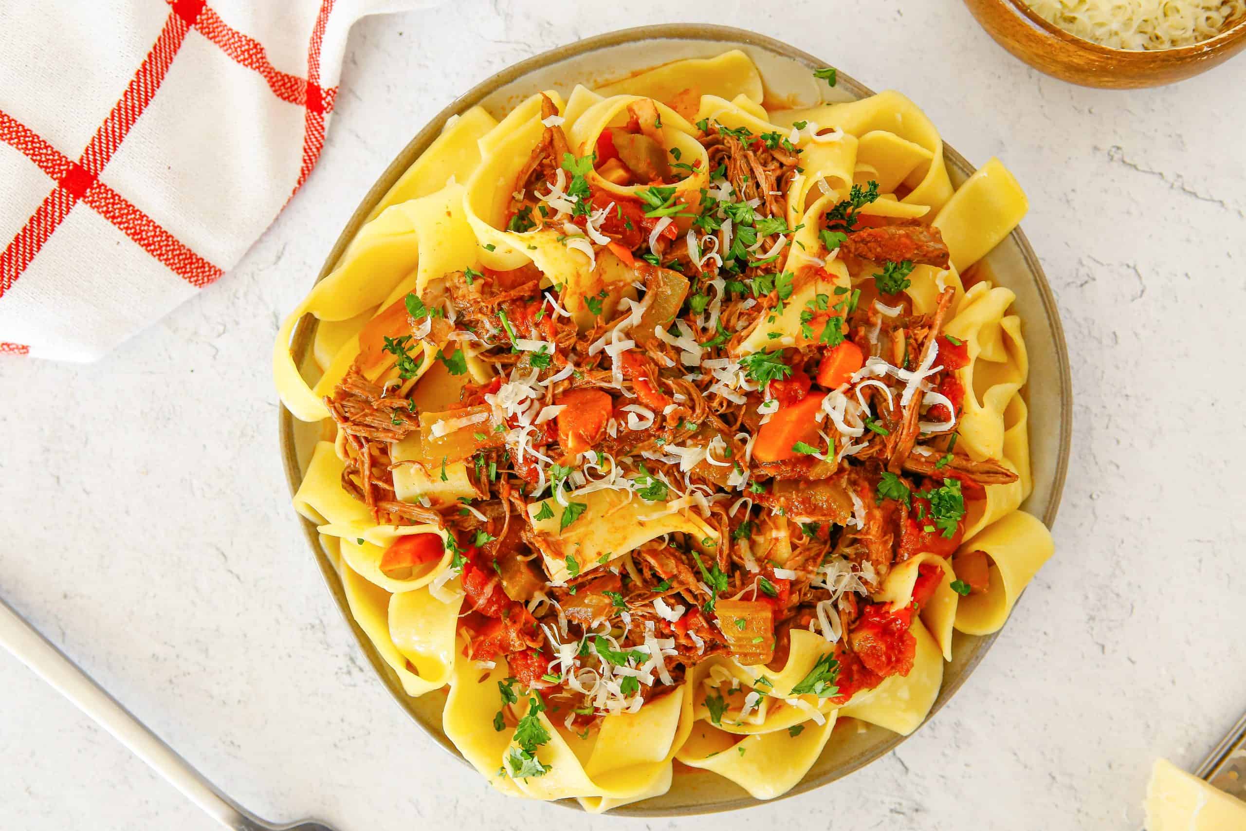 Overhead view of beef ragu on pappardelle pasta.