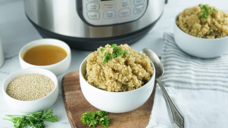 Cooke quinoa in a white bowl with ingredients beside it and Instant Pot in background.