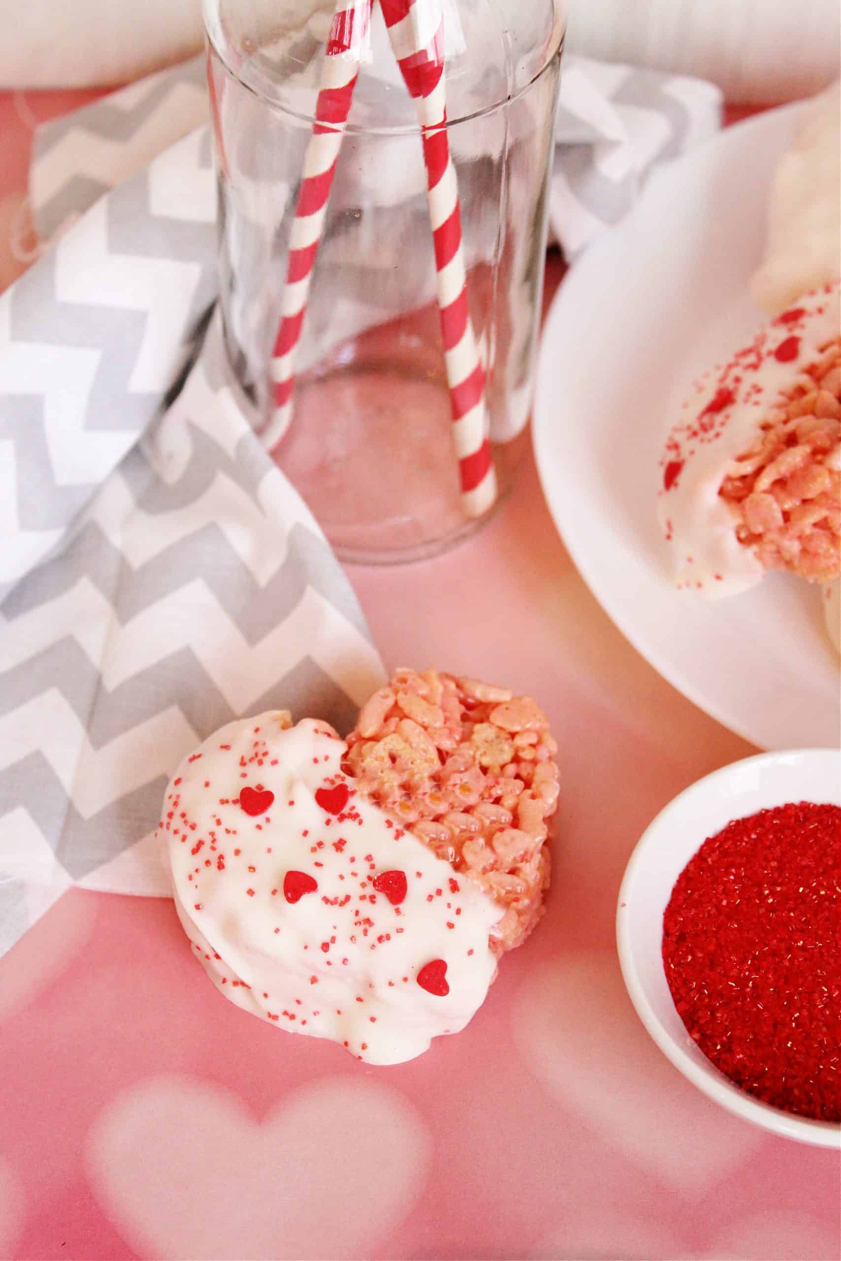 Pink heart shaped Rice Krispie treat dipped in white chocolate with sprinkles.