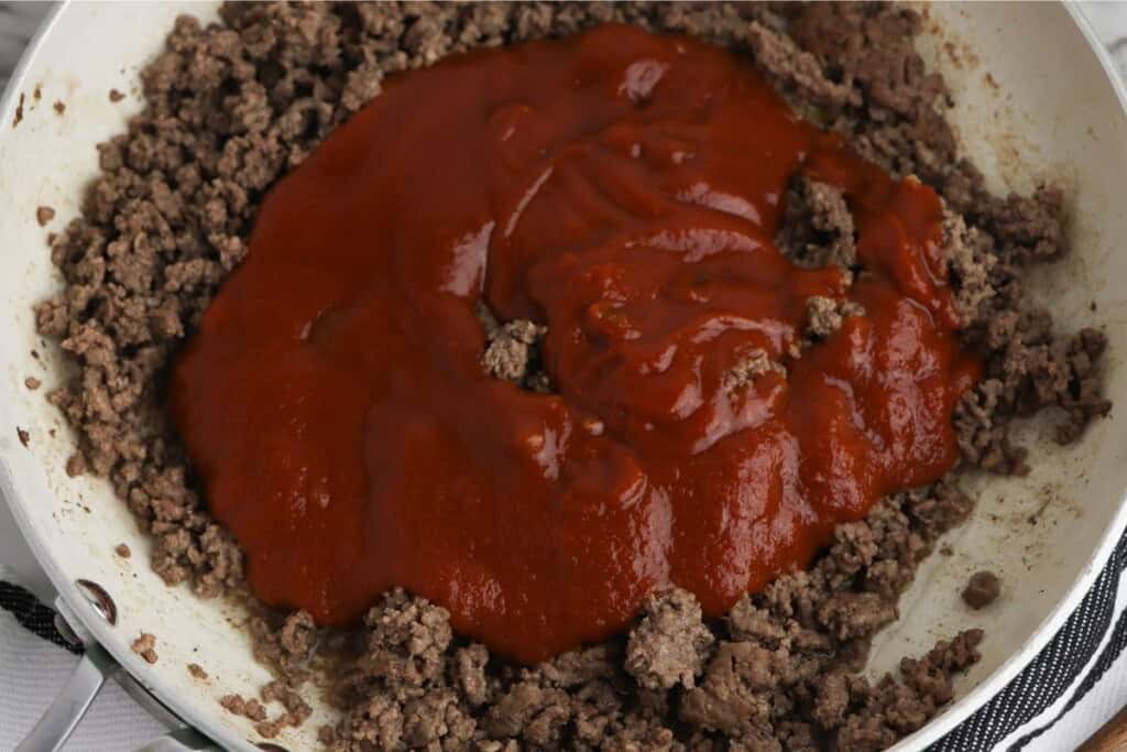 adding Manwich sloppy joe sauce to cooked ground beef